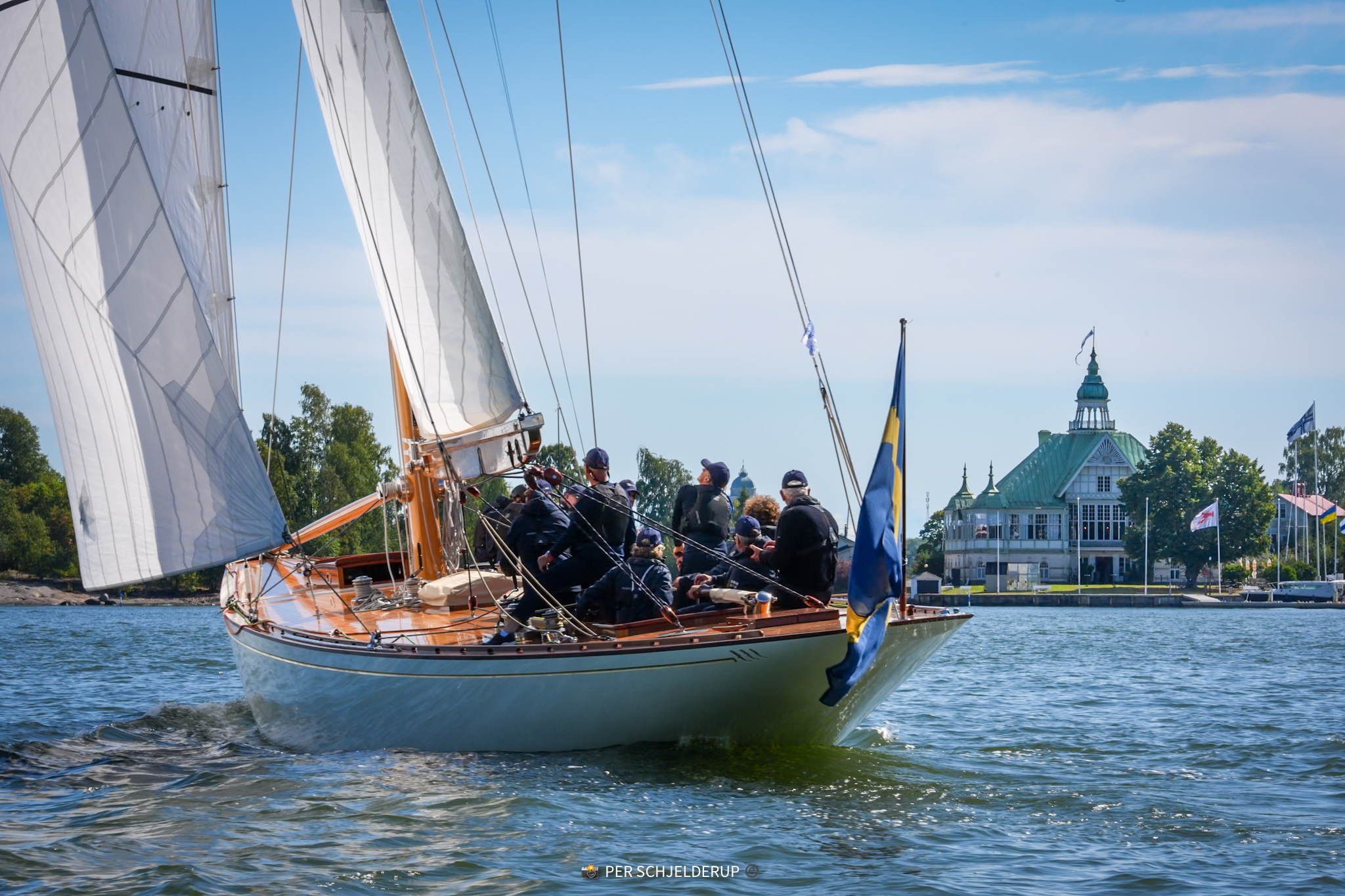 Princess Svanevit under the Swedish ensign, passing the yacht club pavilion in Helsinki harbour.
